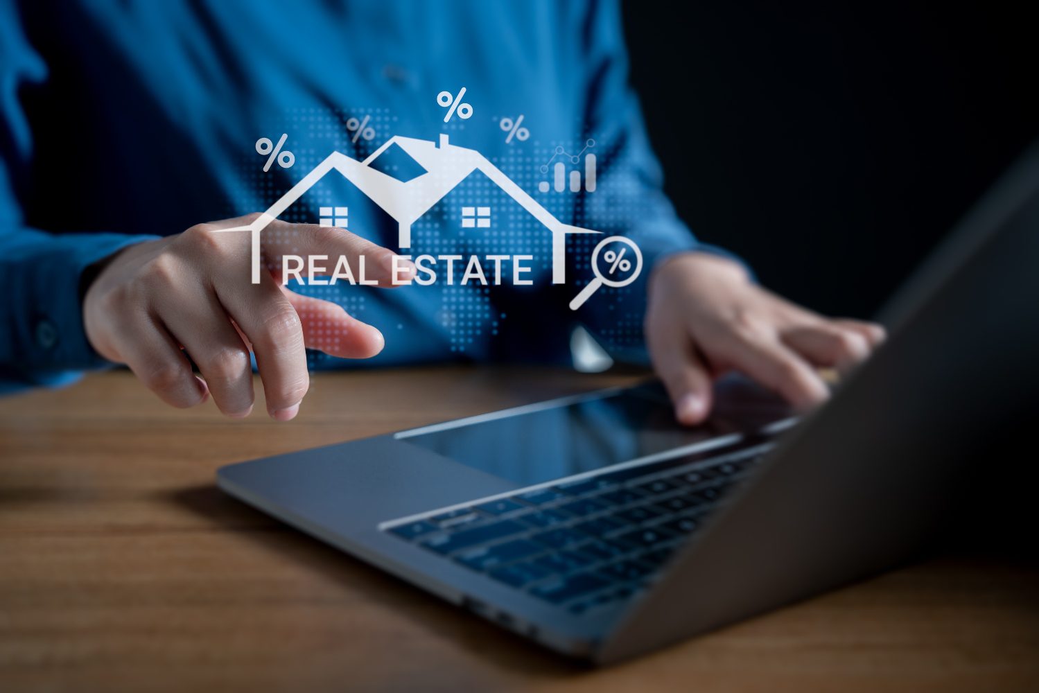 Person using laptop with real estate icons.